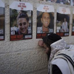 Ein Mann betet vor Plakaten mit den Gesichtern der Geiseln, die von der Hamas entführt wurden.