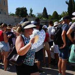 Touristen tragen Hüte und benutzen Fächer und Regenschirme um sich vor der Hitze zu schützen.