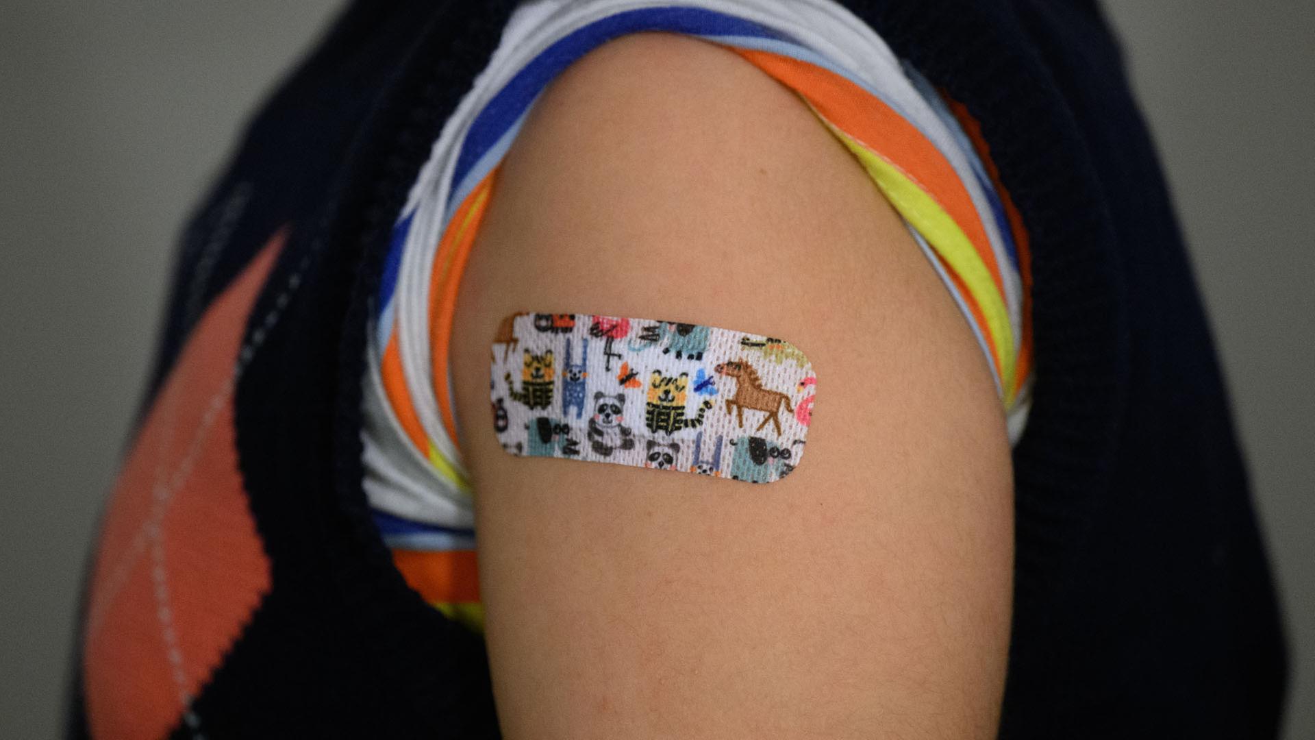 Ein Pflaster mit bunten Tiermotiven klebt nach einer Impfung auf dem Oberarm eines Kindes. | picture alliance/dpa/dpa-Zentral
