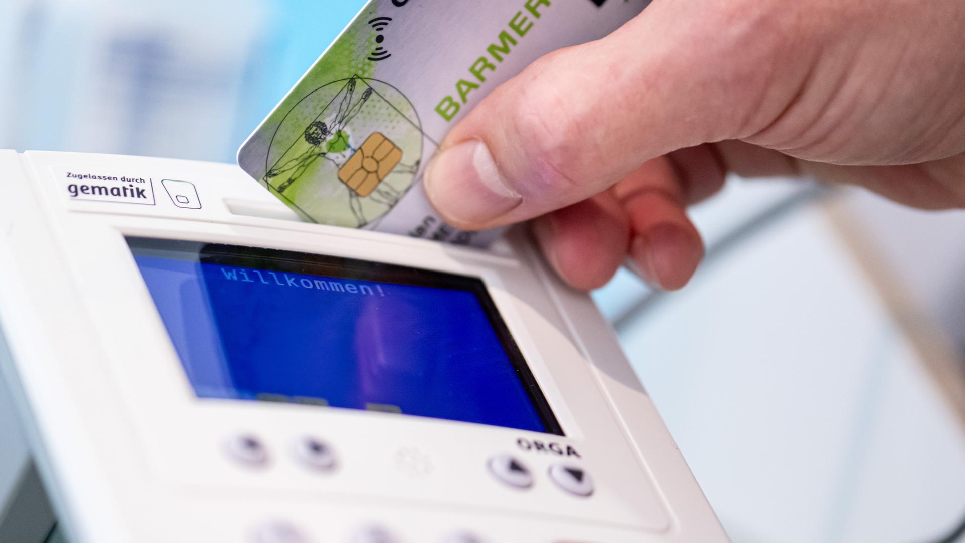 Eine Hand steckt eine Gesundheitskarte in ein Lesegerät. | dpa