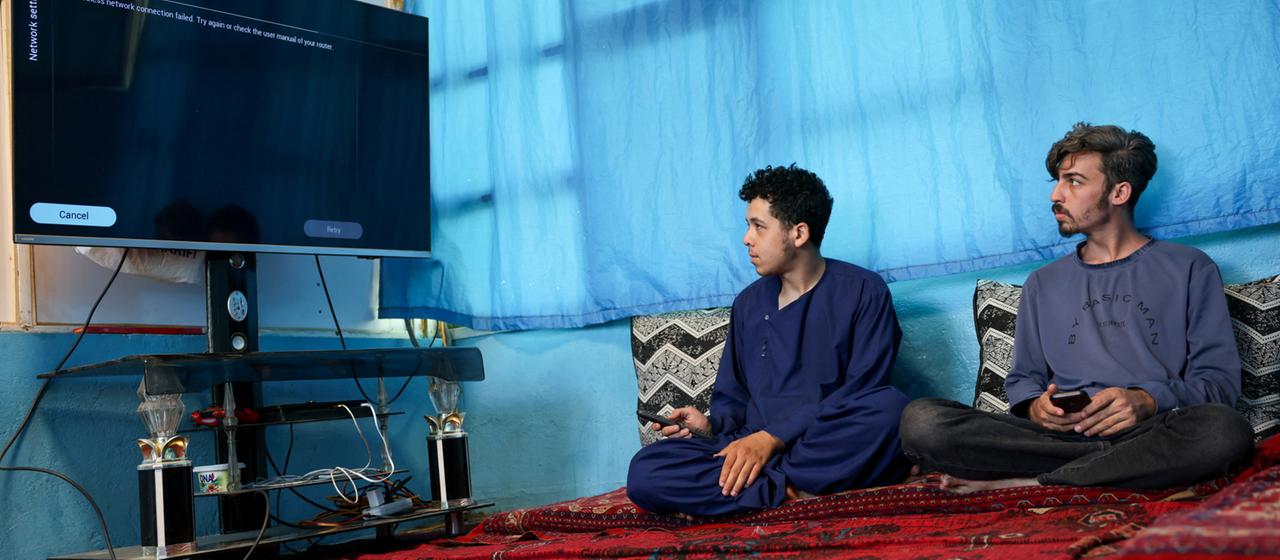 Zwei Männer versuchen, ihren Smart-TV zu Hause in Kabul mit dem Internet zu verbinden.