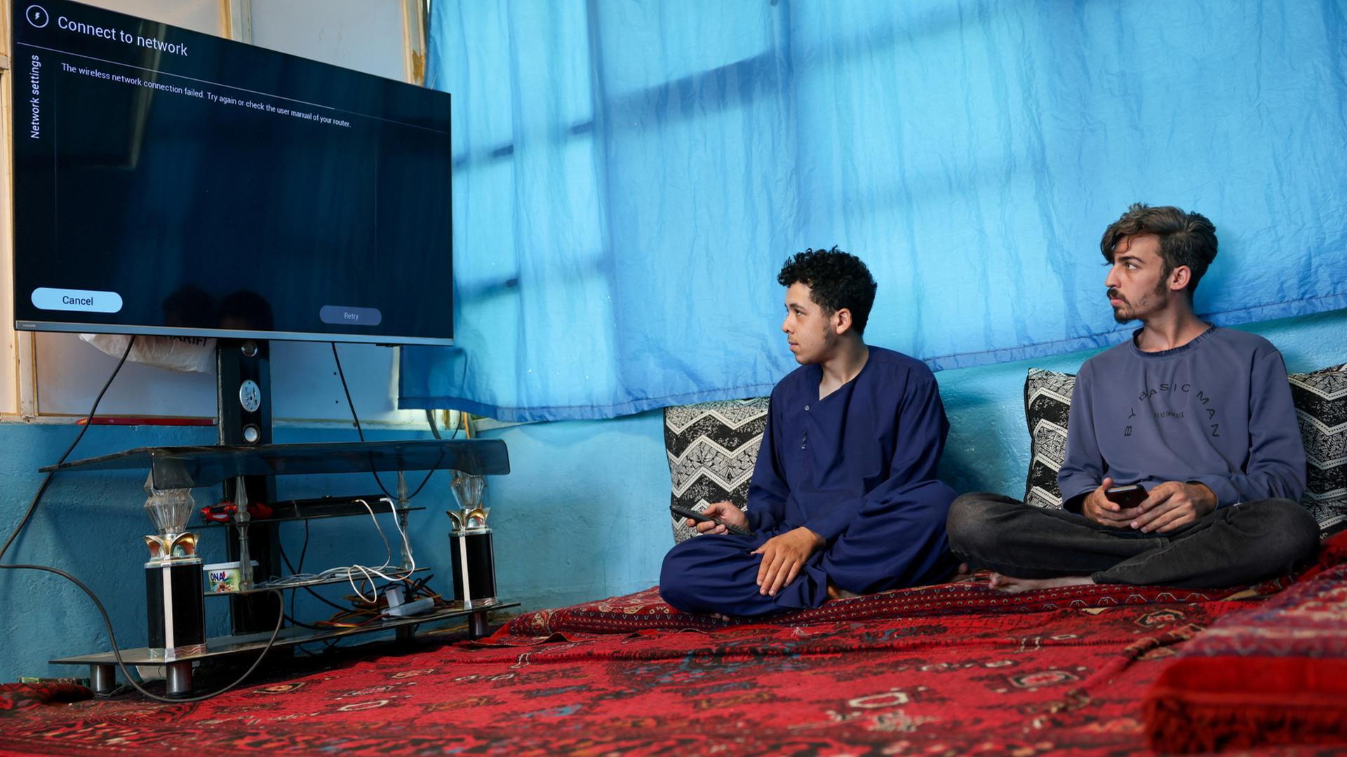 Männer in Kabul (Afghanistan) schauen auf einen schwarzen Bildschirm.  | REUTERS