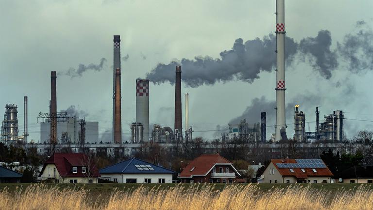 Schornsteine der PCK-Raffinerie und anderer Unternehmen im Industriepark Schwedt. Im Vordergrund Wohnhäuser.