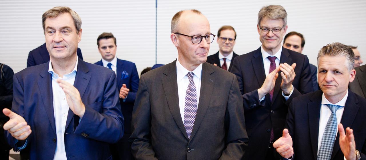 Friedrich Merz erhält Beifall von Markus Söder und Thorsten Frei während einer Fraktionssitzung im Bundestag