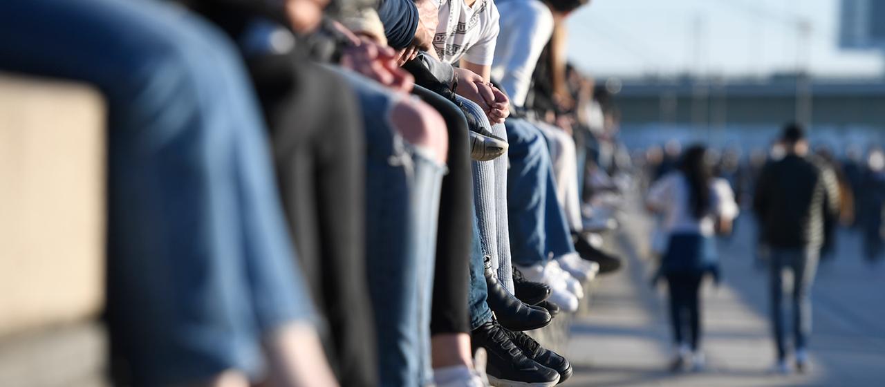 Junge Menschen sitzen auf einer Mauer.