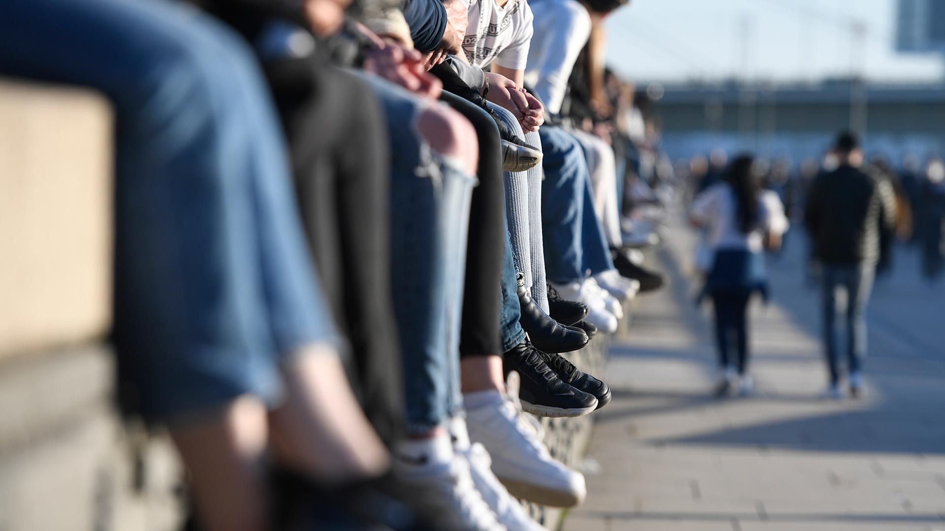 Junge Menschen sitzen auf einer Mauer. | dpa