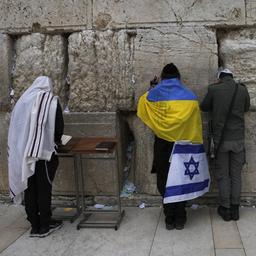 An der Klagemauer in Jerusalem (Israel) betet ein Gläubiger, der eine israelische und eine ukrainische Flagge umgebunden hat