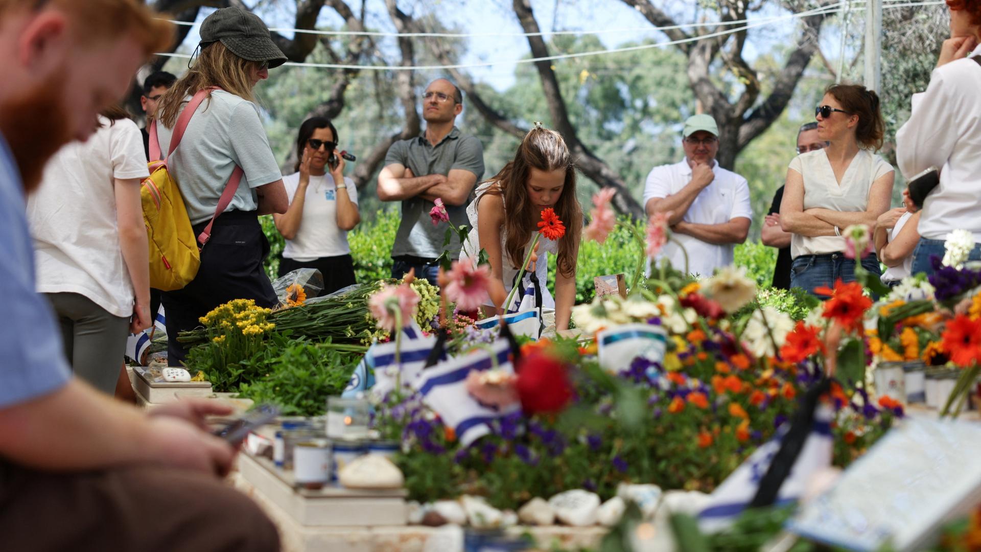 Menschen trauern an den Gräbern am israelischen Gedenktag auf einem Friedhof in Tel Aviv. | REUTERS