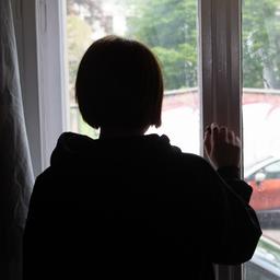 Eine Jugendliche blickt aus einem Fenster.