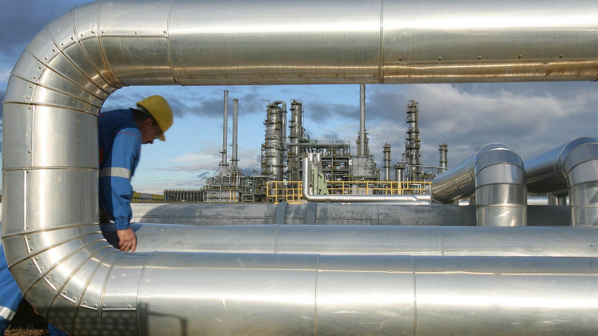 In der Raffinerie in Leuna geht ein Mitarbeiter an den Rohren einer Pumpstation entlang. | picture-alliance/ dpa