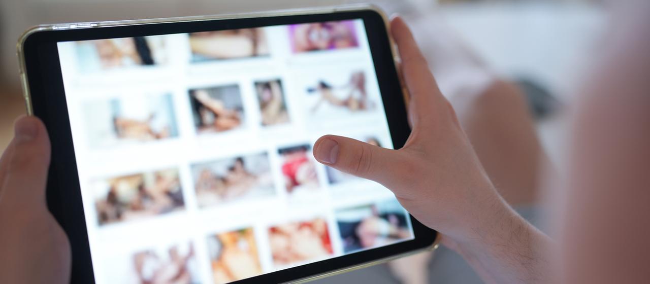 Eine Person schaut sich eine Pornoseite auf dem tablet an.