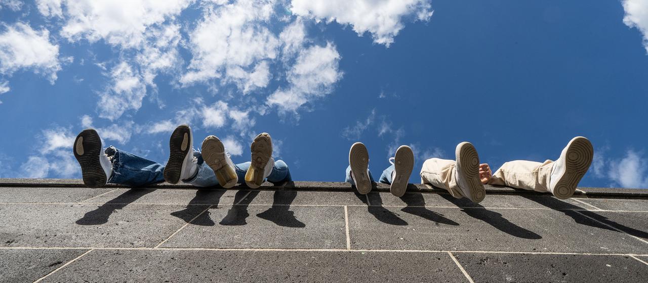 Füße von Jugendlichen, die auf einer Mauer sitzen. | dpa Füße von Jugendlichen, die auf einer Mauer sitzen.