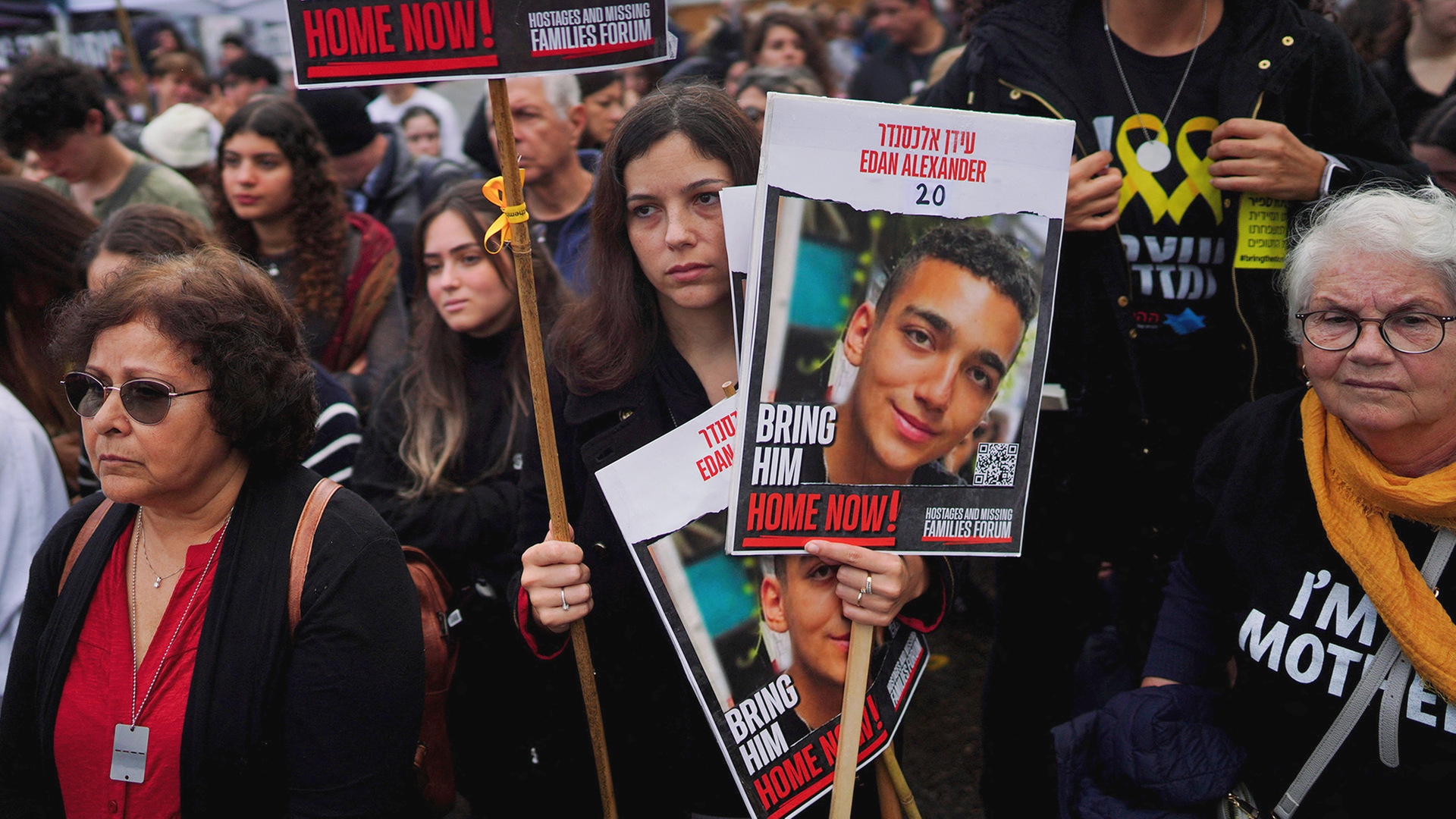 Menschen auf einer Kundgebung halten Plakate.