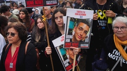 Menschen auf einer Kundgebung halten Plakate.