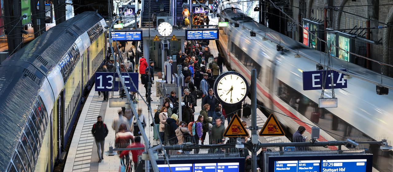 Reisende sind am Hauptbahnhof Hamburg auf dem Bahnsteig zwischen einem ICE und einem Regionalzug unterwegs. 