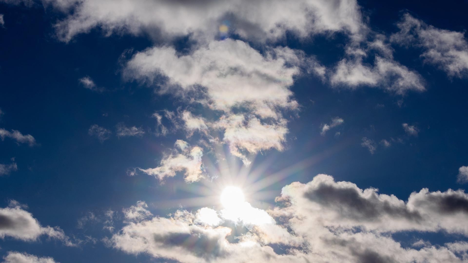 Die Sonne scheint zwischen Wolken hindurch. | dpa