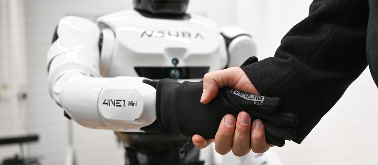 Handschlag zwischen einem Menschenund  einem humanoiden Roboter der Firma Neura.