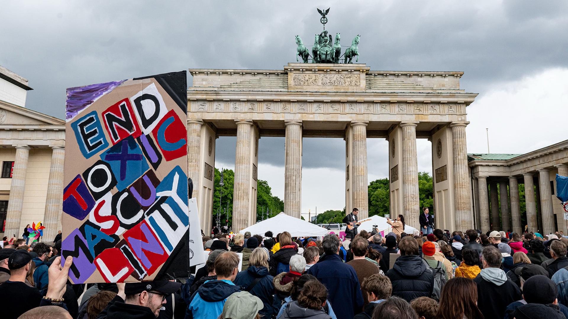: Menschen nehmen an der Demonstration Â«MÃ¤nner gegen GewaltÂ» gegen geschlechterspezifische und sexualisierte Gewalt am Pariser Platz mit einem Schild mit der Aufschrift 