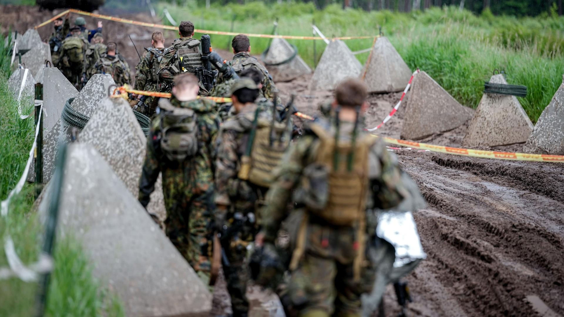 Panzergrenadiere der Bundeswehr aus der Puma-Schützenpanzereinheit gehen bei einer Gefechtsübung in Litauen über einen Weg.  | Kay Nietfeld/dpa