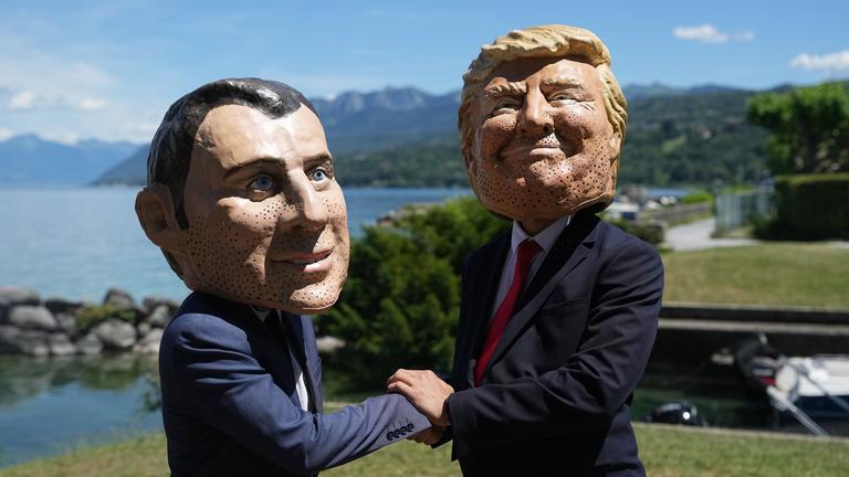 Bei einer Aktion der Organisation Oxfam in Evian sind Menschen mit Macron- und Trump-Masken zu sehen.
