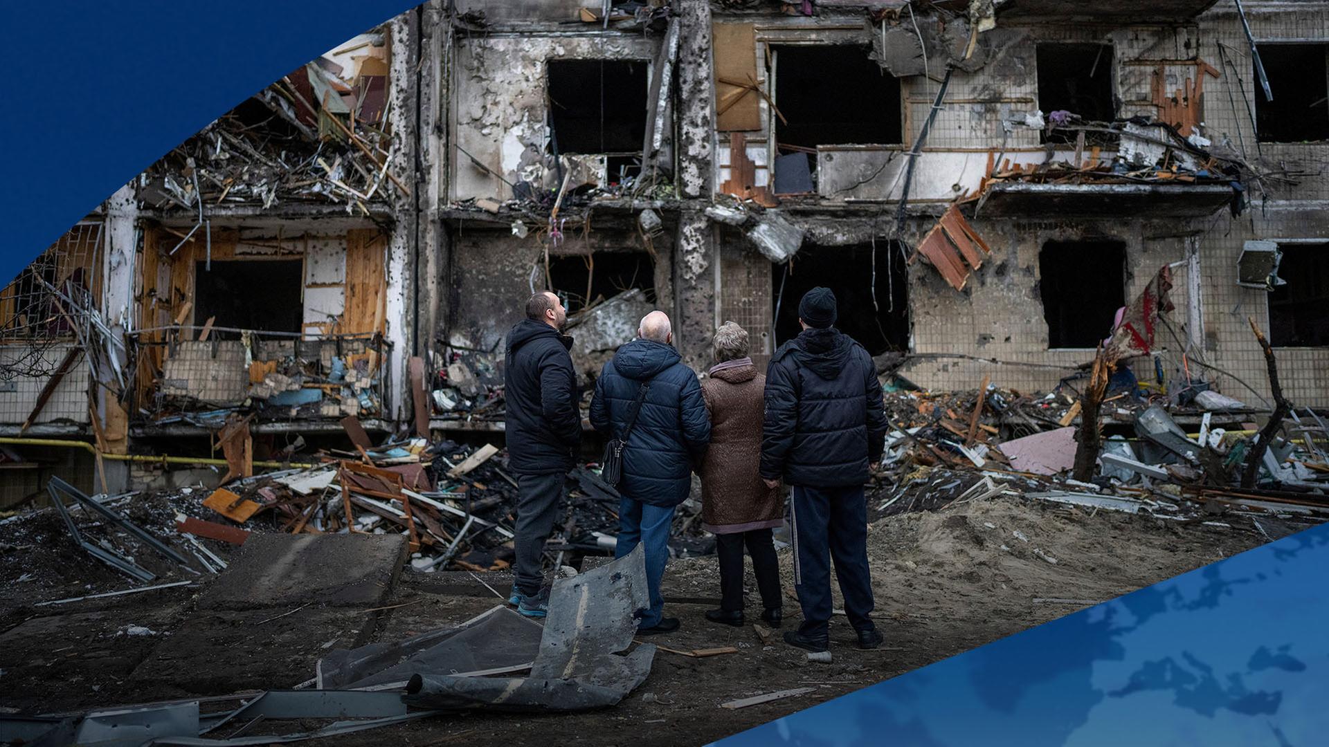 Menschen schauen auf ein zerbombtes GebÃ¤ude in Kyiv, Ukraine. | AP
