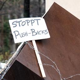 Ein Aktivist befestigt ein Schild mit der Aufschrift "Stoppt Push-backs".
