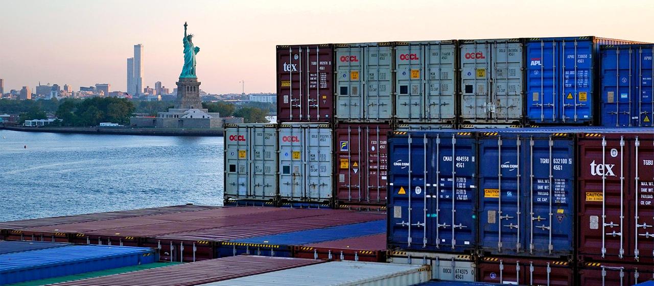 Statue of Liberty, New York, im Vordergrund Container auf einem Frachtschiff.