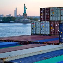 Statue of Liberty, New York, im Vordergrund Container auf einem Frachtschiff.