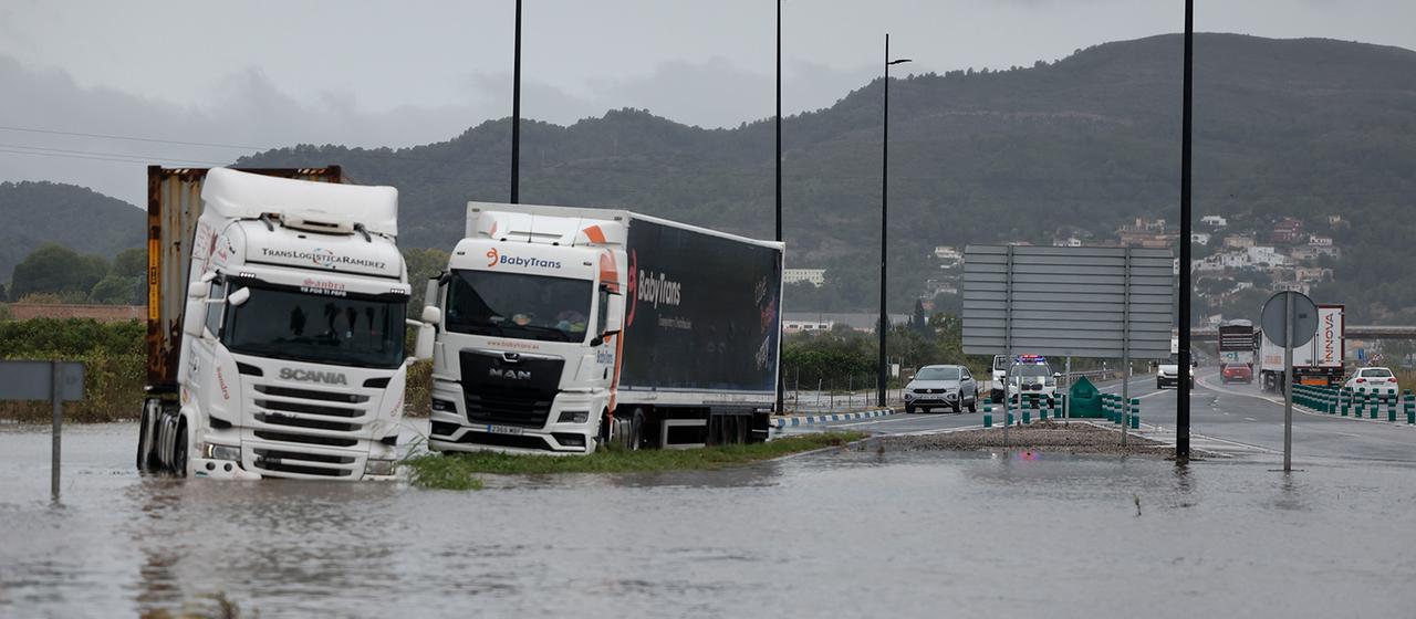 Zwei Lastwagen stehen in einer überfluteten Fernstraße bei Valencia, Spanien.