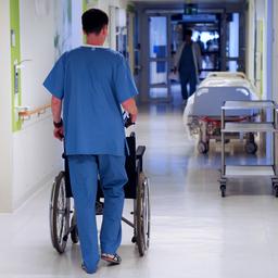 Ein Krankenpfleger schiebt einen Rollstuhl über den Krankenhausflur.