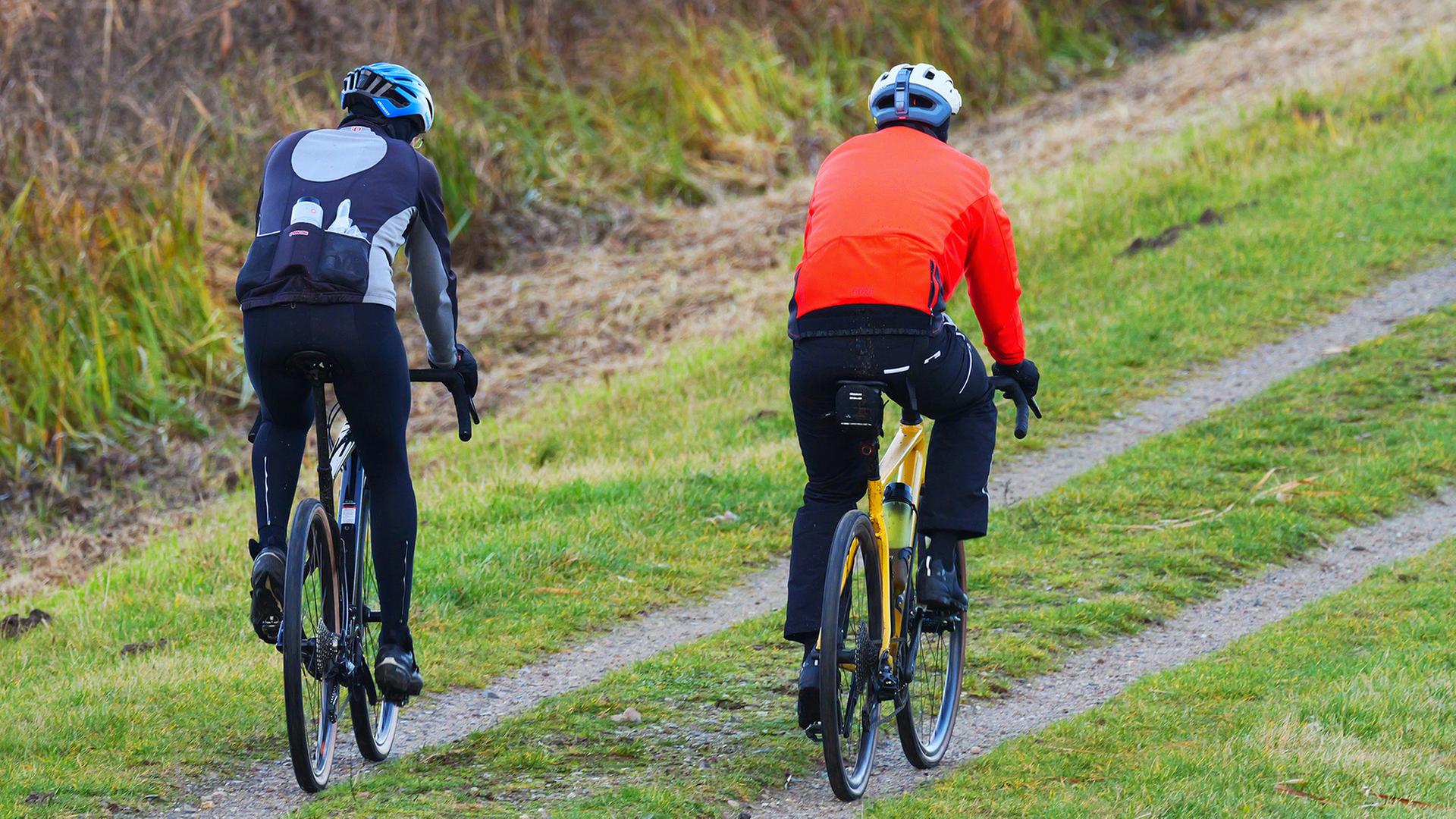 Zwei M�nner fahren in Outdoor-Kleidung auf Gravel Bikes �ber einen Feldweg.  | picture alliance/dpa