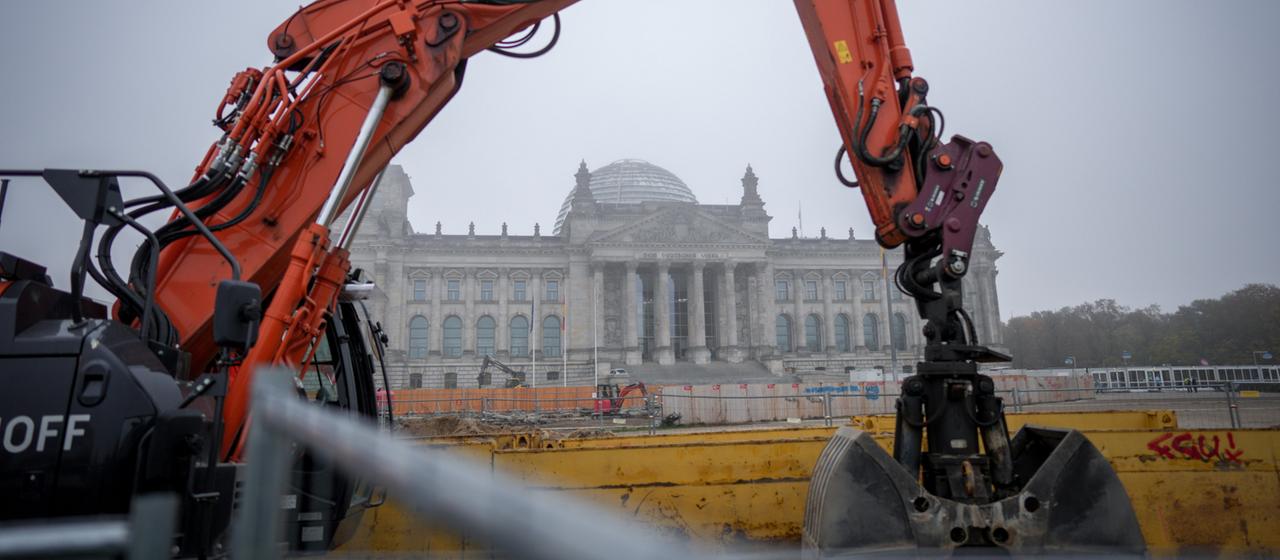 Ein Bagger steht auf einer Baustelle im Nebel vor dem Reichstagsgebäude in Berlin.