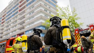 Polizeibeamte mit Gasmasken und Feuerwehrleute stehen vor dem Hochhaus in Ratingen (Archivbild)