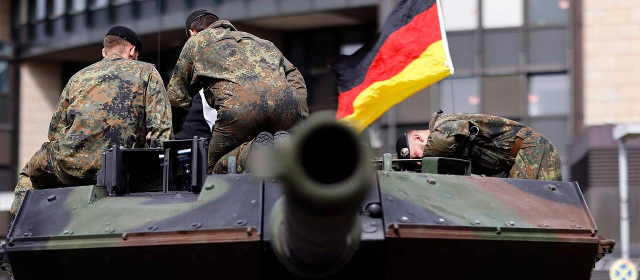 Bundeswehrsoldaten mit einer Deutschlandfahne auf einem Panzer.