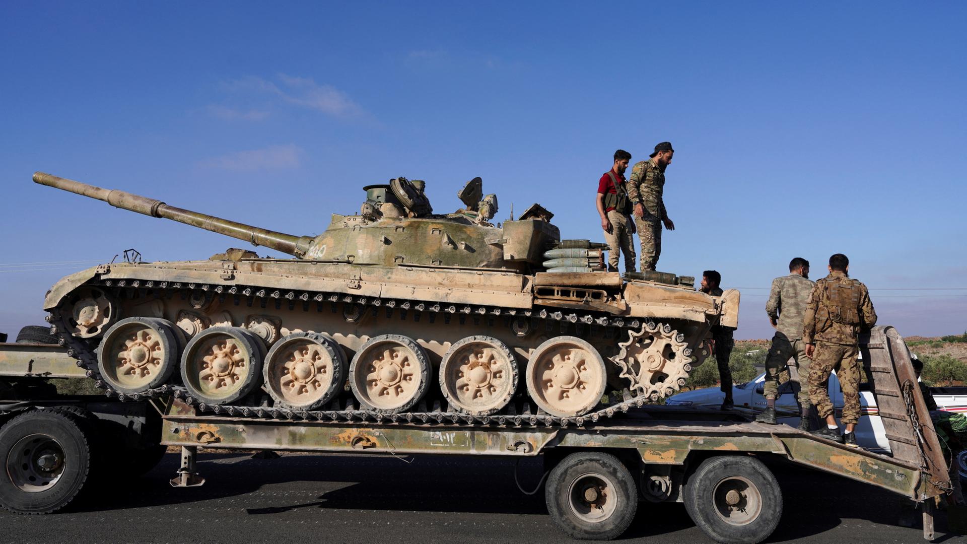 Soldaten syrischer Truppen verladen einen Panzer. | REUTERS