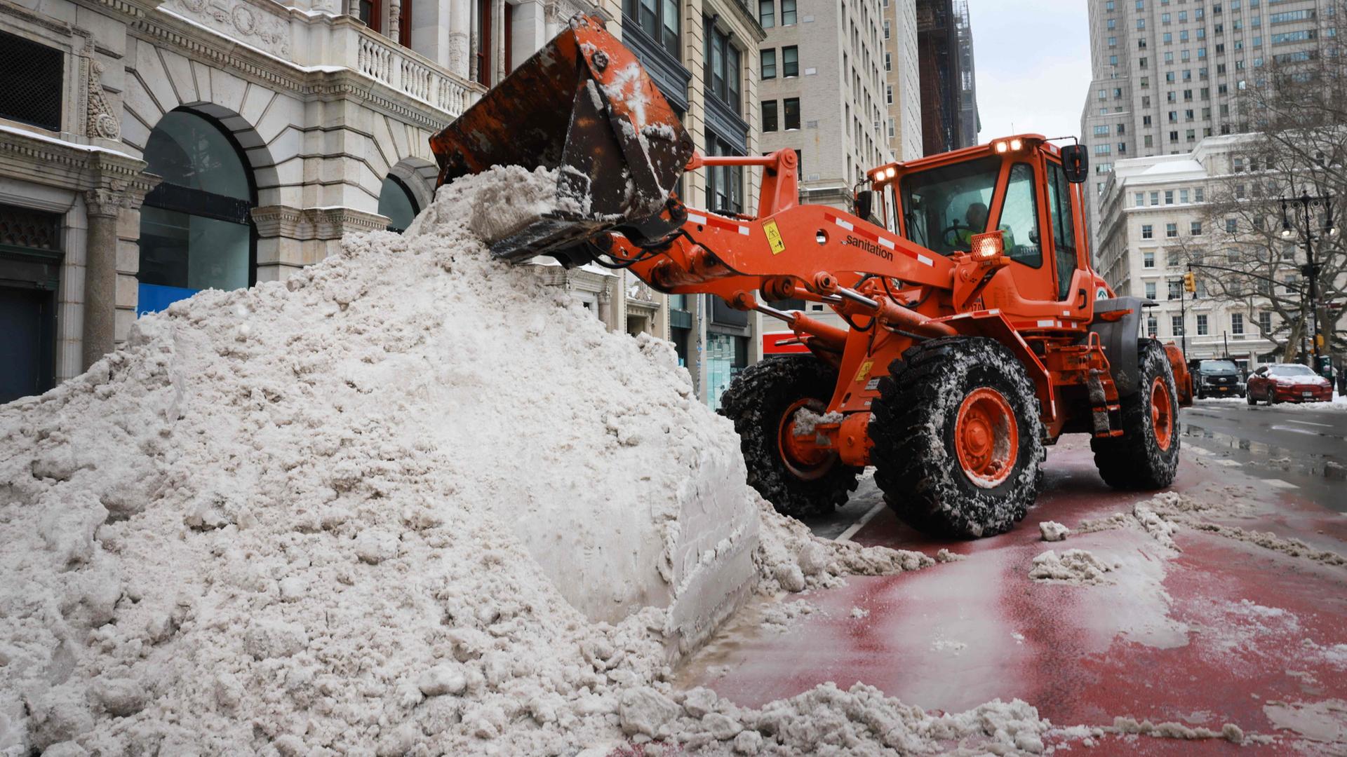 Ein Schneepflug türmt Schnee an den Rand einer Straße in Manhatten, New York | Getty Images via AFP