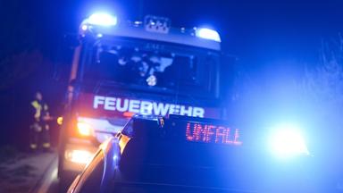 Feuerwehrfahrzeug und Streifenwagen mit Blaulicht und LED-Anzeige "Unfall"