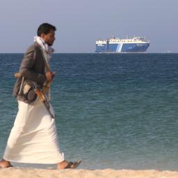 Ein Huthi-Kämpfer läuft über den Strand, im Hintergrund die "Galaxy Leader" zu sehen