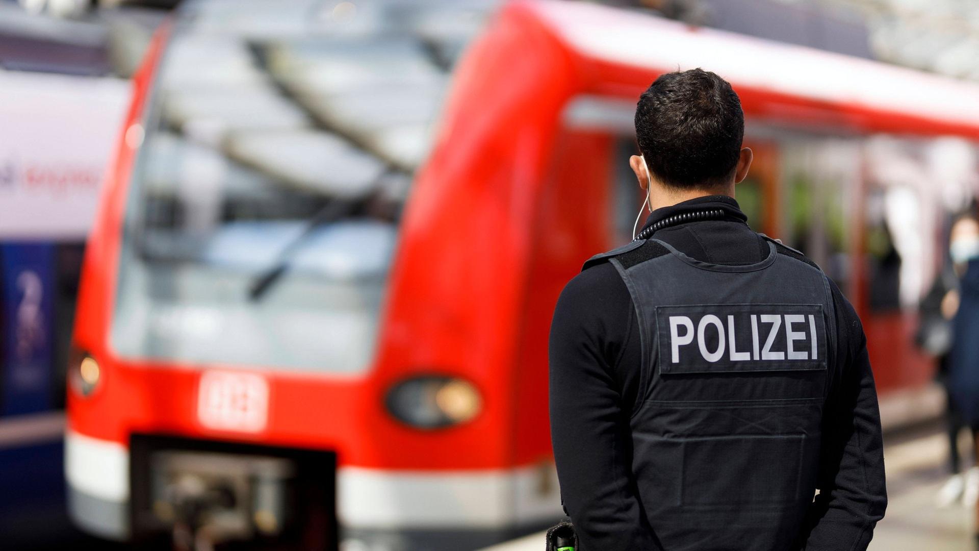 Ein Bundespolizist steht vor einem roten Zug an einem Bahngleis. | IMAGO / Future Image (Symbolbild)