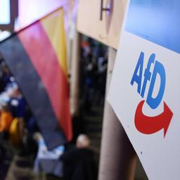 Ein Logo der AfD hängt neben eine Deutschlandfahne