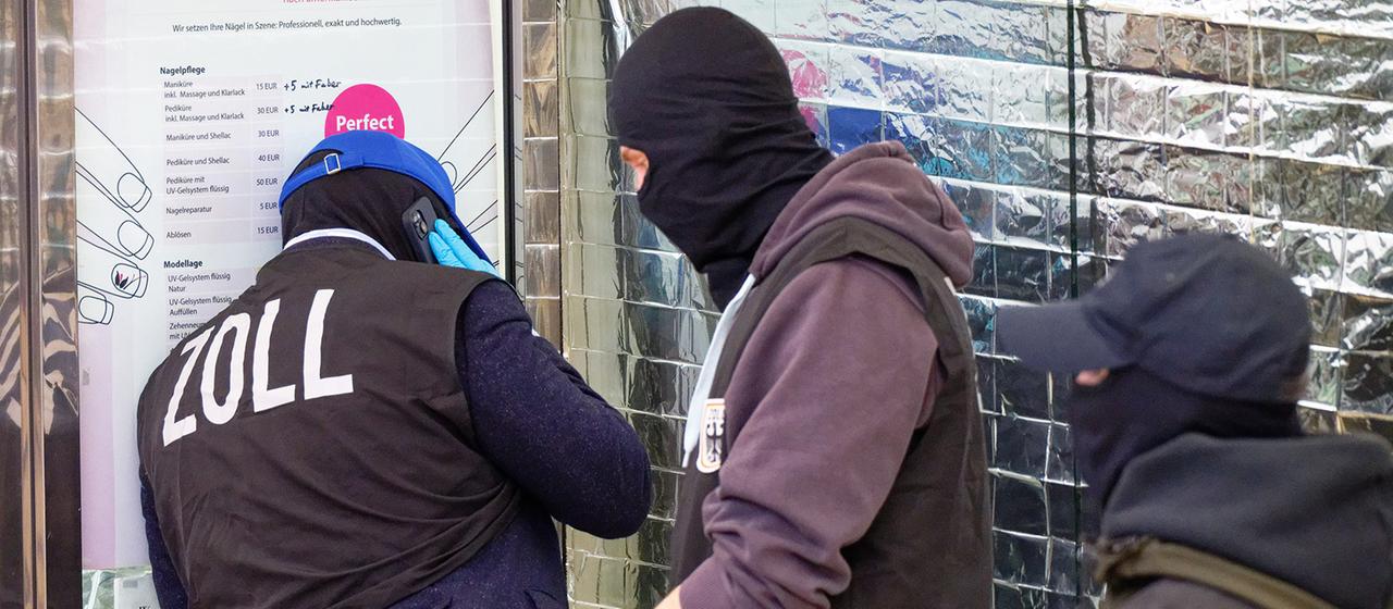 Zollbeamte stehen vor einem Nagelstudio in der Kölner Innenstadt.