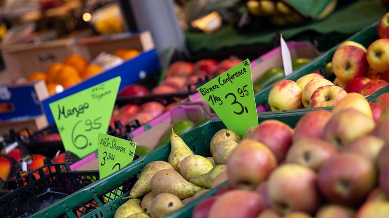 Lebensmittelpreise sind an einem Marktstand ausgeschildert.
