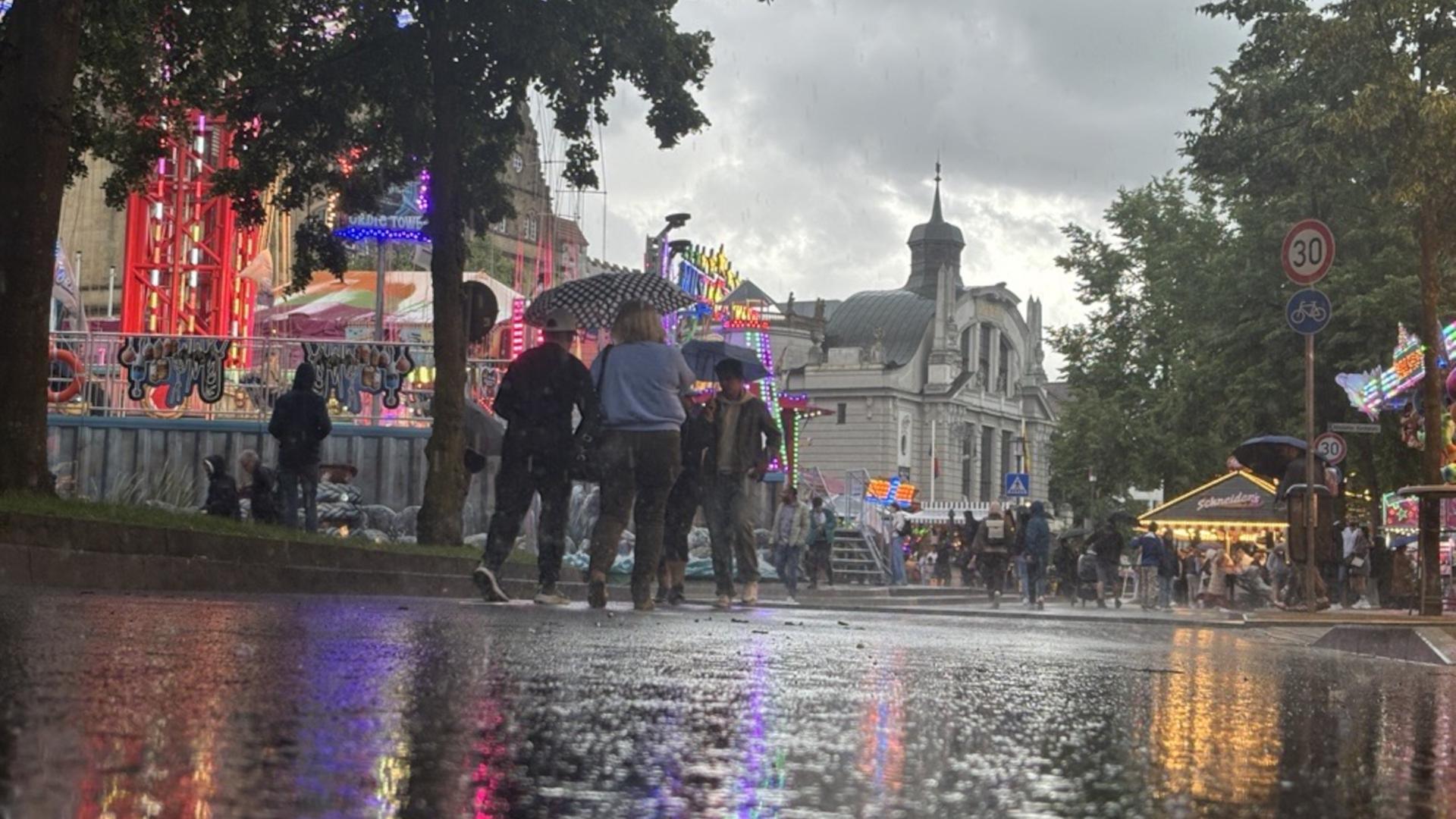 Menschen laufen mit Regenschirmen durch den Regen auf dem Bielefelder Stadtfest | WDR/ Simon Kaufmann