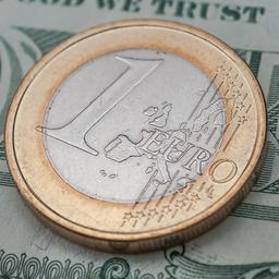 Euromünze auf einem Dollarschein.