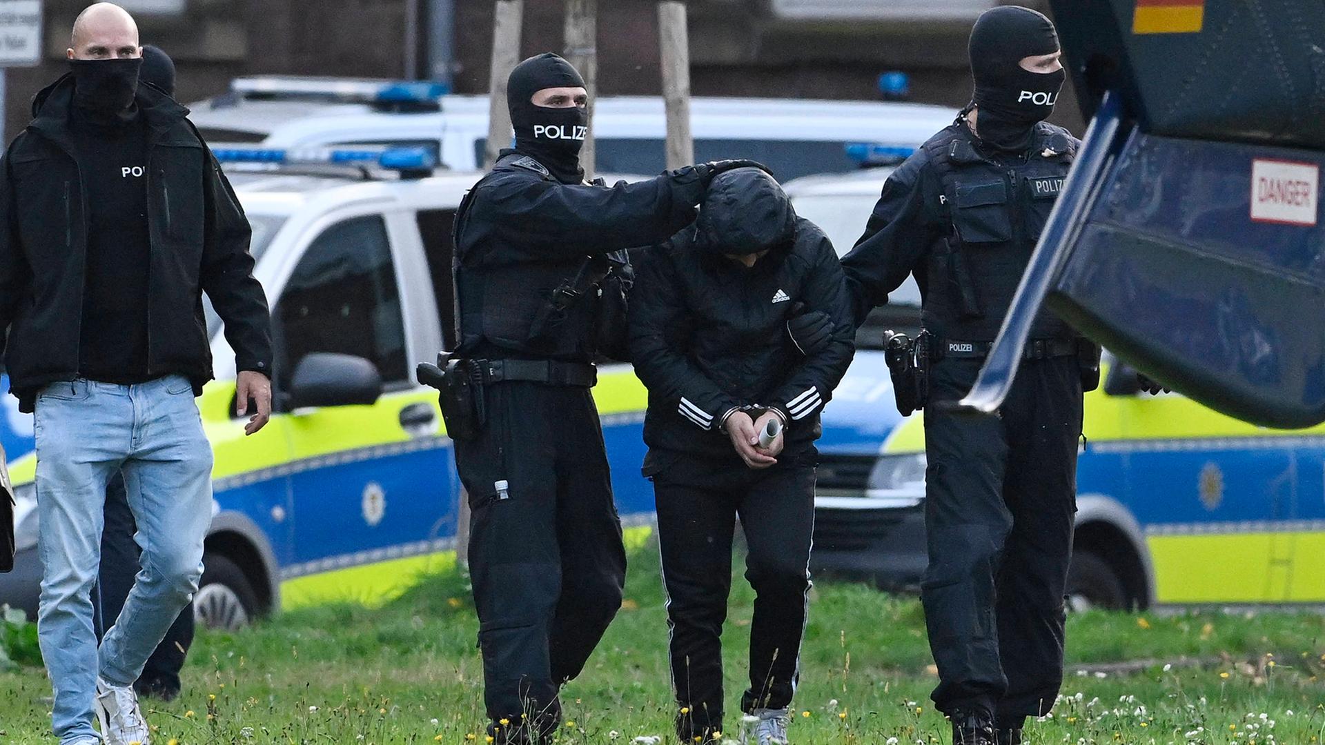 Omar A. wird von Polizisten abgeführt. | IMAGO/brennweiteffm
