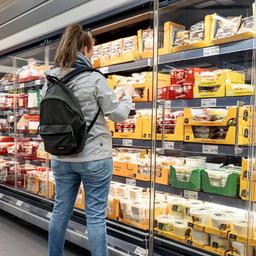 Eine Kundin steht in einem Supermarkt vor dem Kühlregeal.