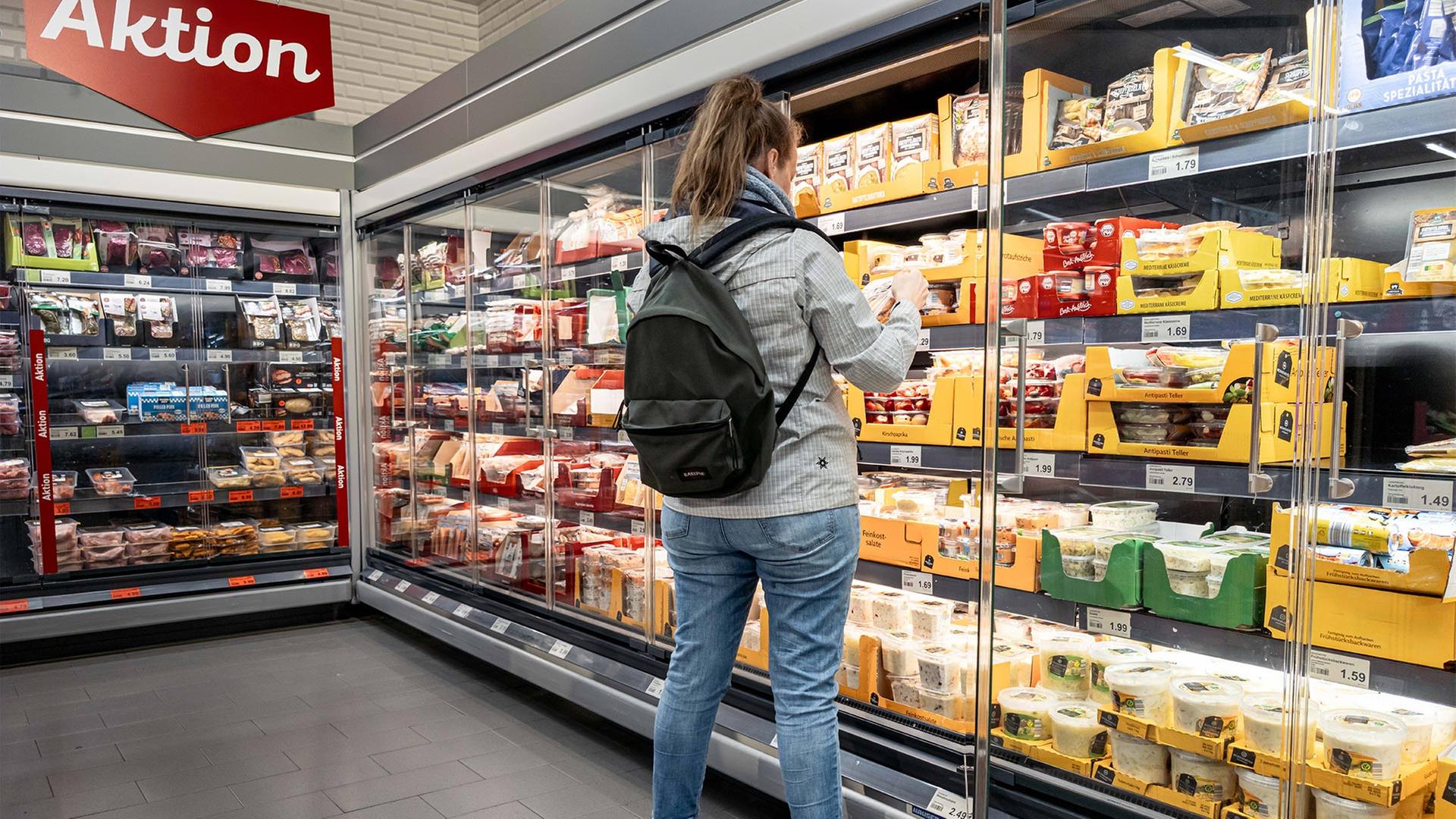 Eine Kundin steht in einem Supermarkt vor dem Kühlregeal. | picture alliance/dpa