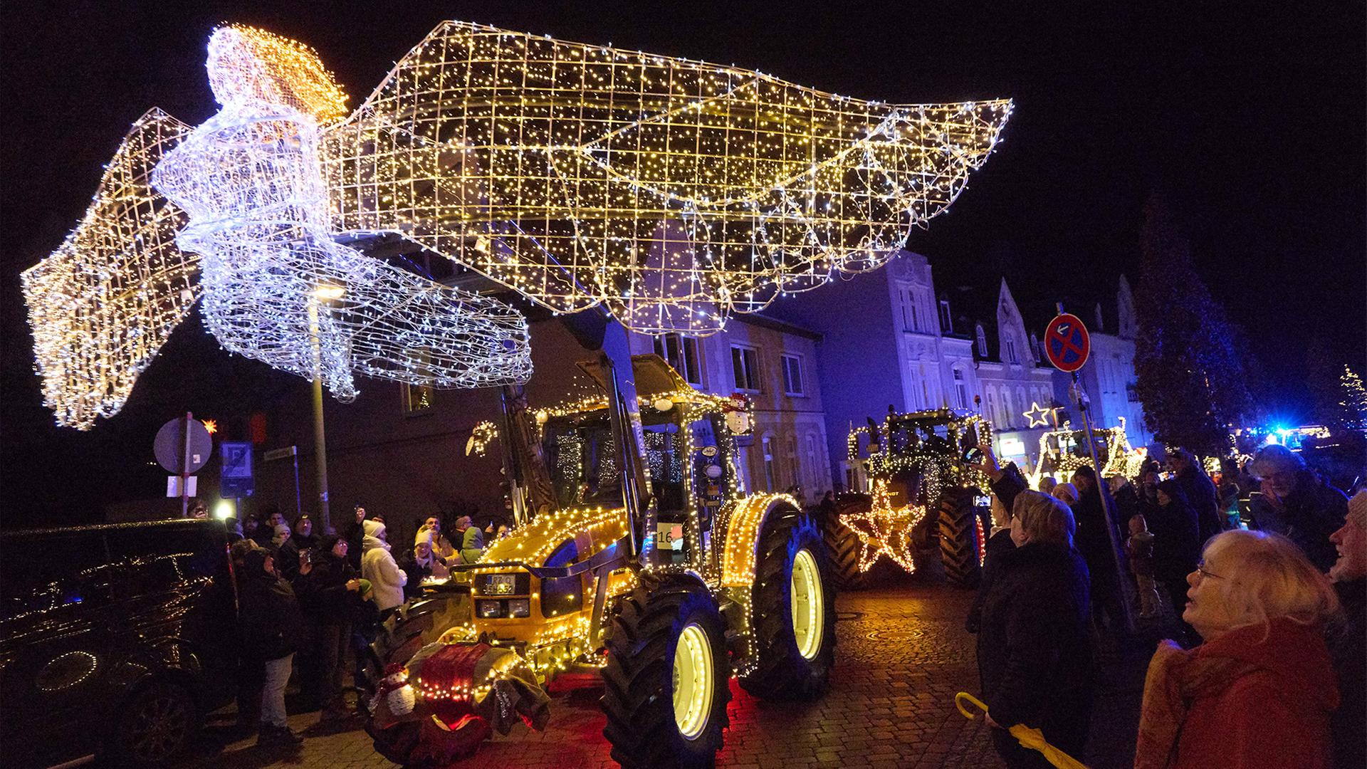 Eine Parade mit geschmÃ¼ckten und beleuchteten Treckern fÃ¤hrt durch einen Ort. | dpa
