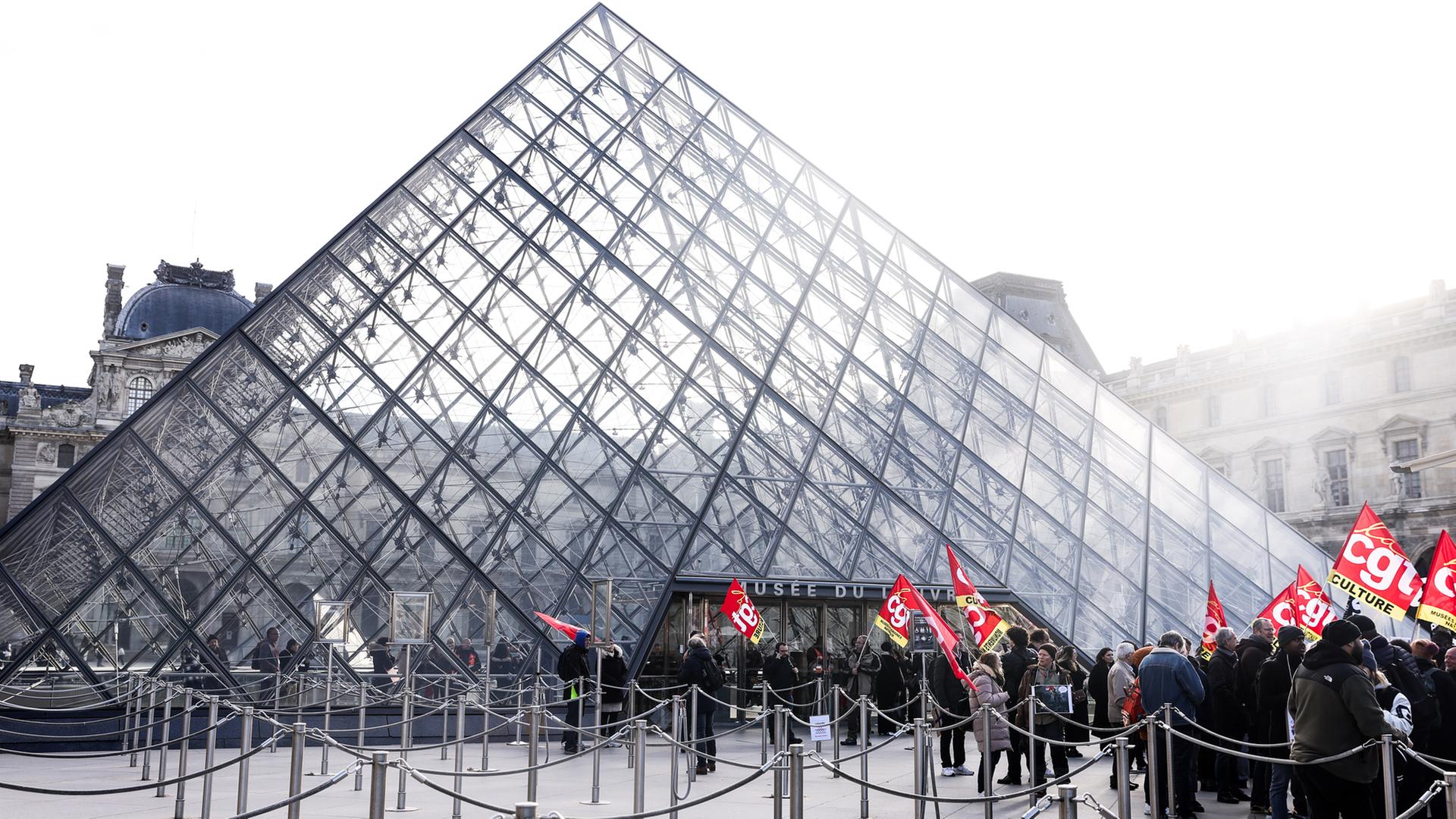Mitarbeiter des Louvre-Museums in Paris halten Banner vor dem Eingang hoch. | EPA
