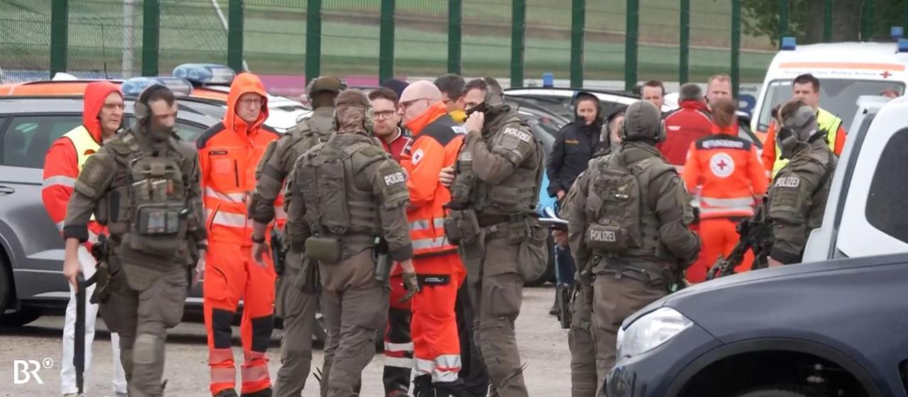 Ein Mann mit schwarzem Helm von hinten mit Warnweste neben einem Auto, auf der Weste steht "Polizei EA-Leiter". In Berngau im Landkreis Neumarkt in der Oberpfalz sind offenbar Schüsse gefallen. Es gibt wohl Verletzte. Anwohner sollen in den Häusern bleiben.